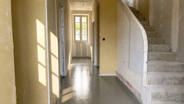 Intérieur en cours de rénovation avec pose de revêtement de sol stratifié gris clair partiellement installé sur chape béton brute
